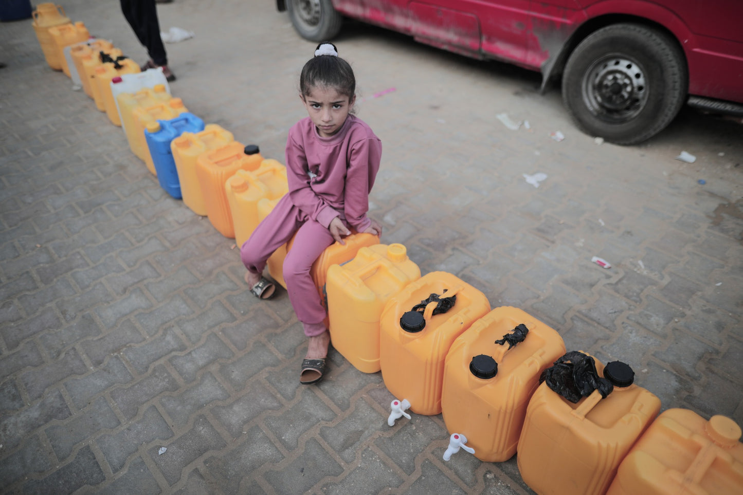 Child Sits on Empty Gallons of Water