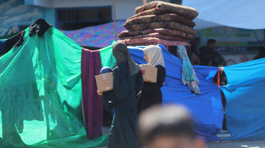 Two Young Women with Aid Boxes at Displacement Site